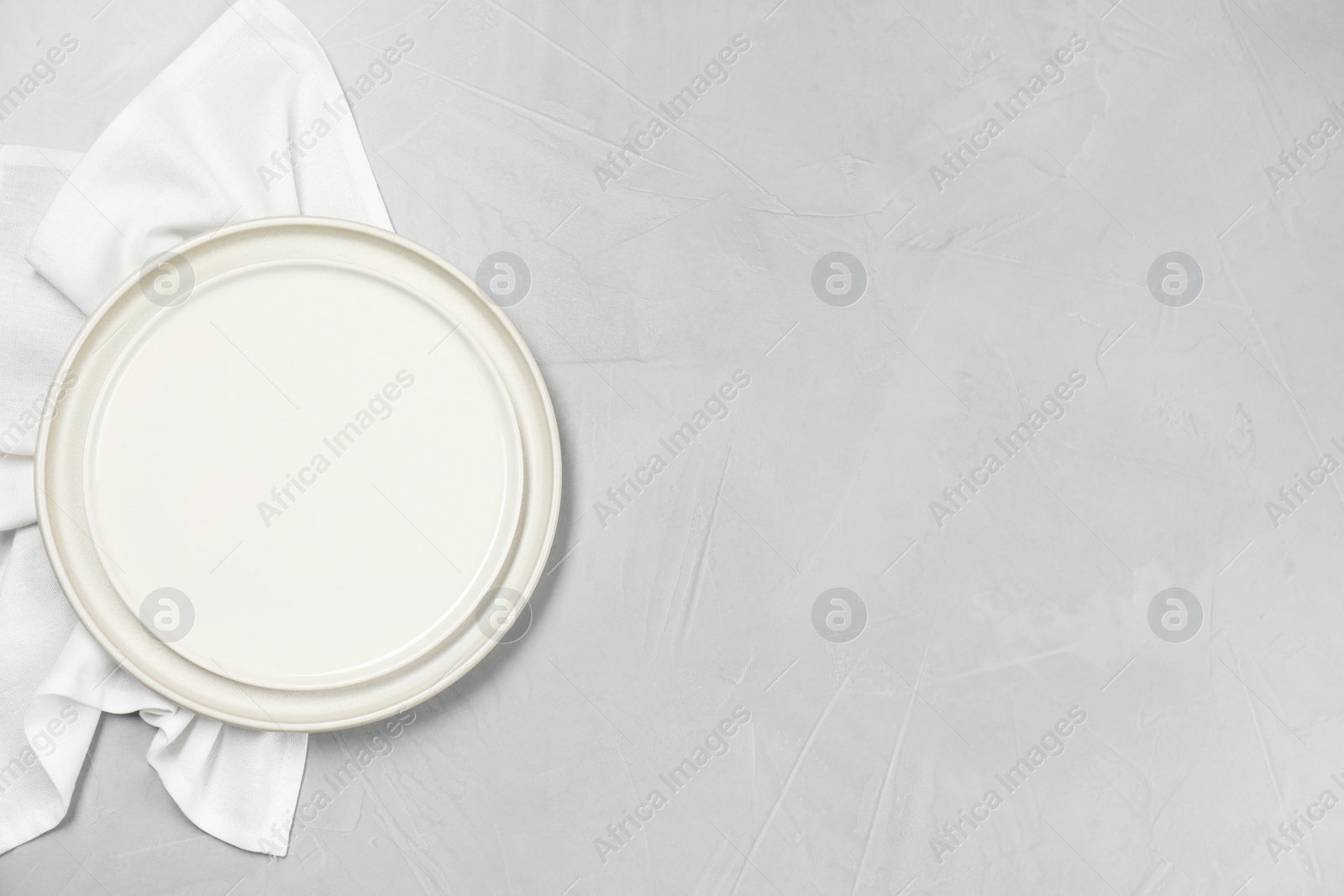 Photo of Elegant plate and napkin on grey table, top view. Space for text