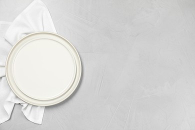 Photo of Elegant plate and napkin on grey table, top view. Space for text