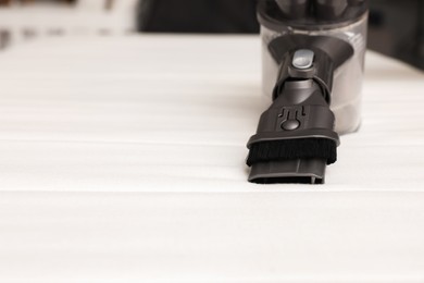 Photo of Modern vacuum cleaner on white mattress indoors, closeup. Space for text