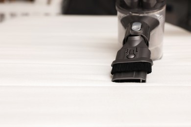 Modern vacuum cleaner on white mattress indoors, closeup. Space for text