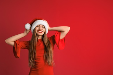 Young beautiful woman in Santa hat on color background. Christmas celebration