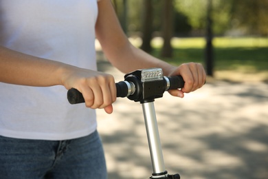 Photo of Woman riding electric kick scooter outdoors, closeup