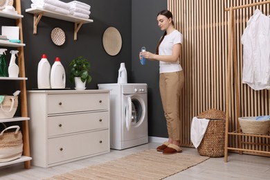 Photo of Woman pouring detergent into cap in laundry room