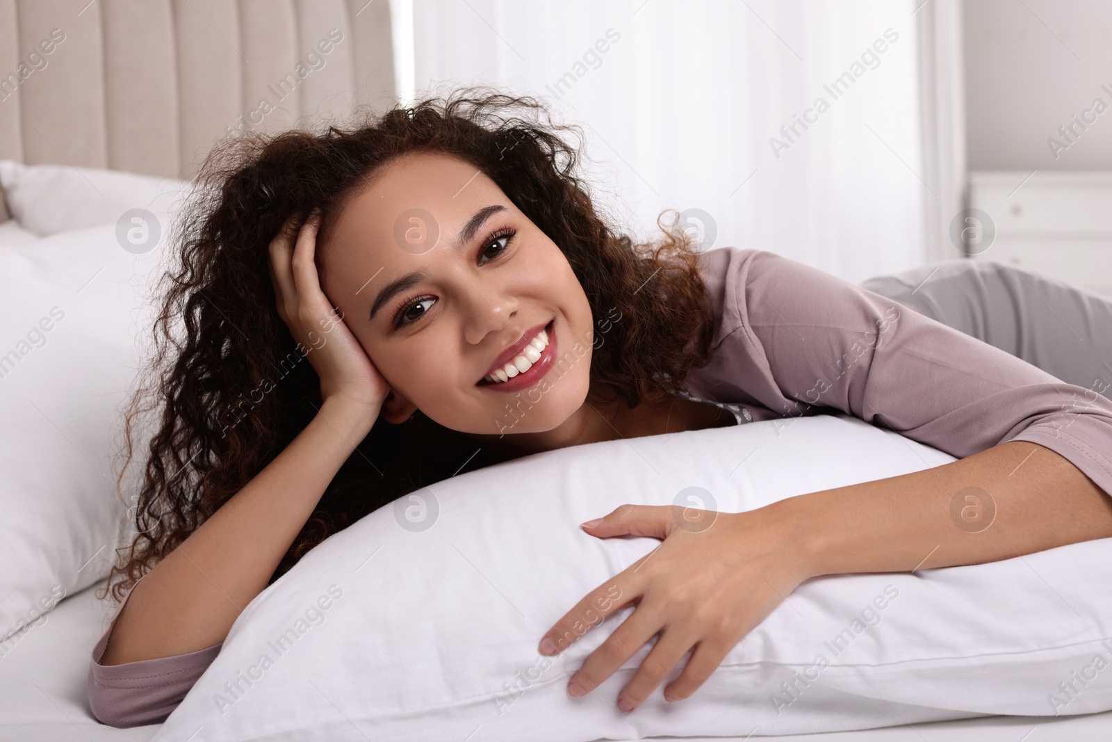 Photo of Happy African American woman lying on bed at home