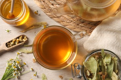 Photo of Freshly brewed tea, honey and dried herbs on white wooden table, flat lay