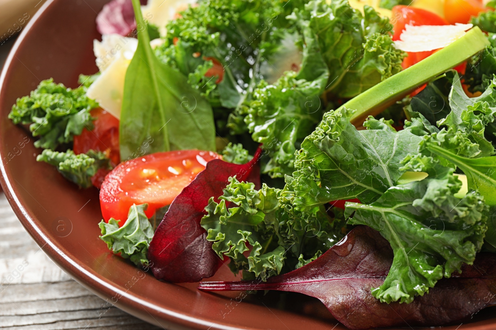 Photo of Tasty fresh kale salad on wooden table, closeup