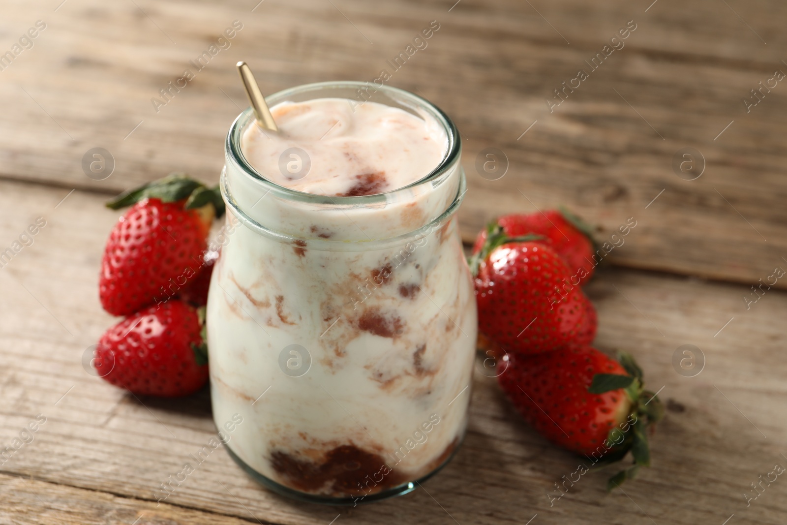 Photo of Tasty yoghurt with jam and strawberries on wooden table, closeup