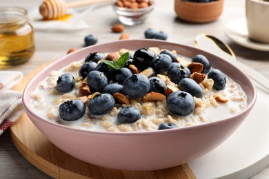 Photo of Tasty oatmeal porridge and ingredients served on wooden table, closeup. Healthy meal