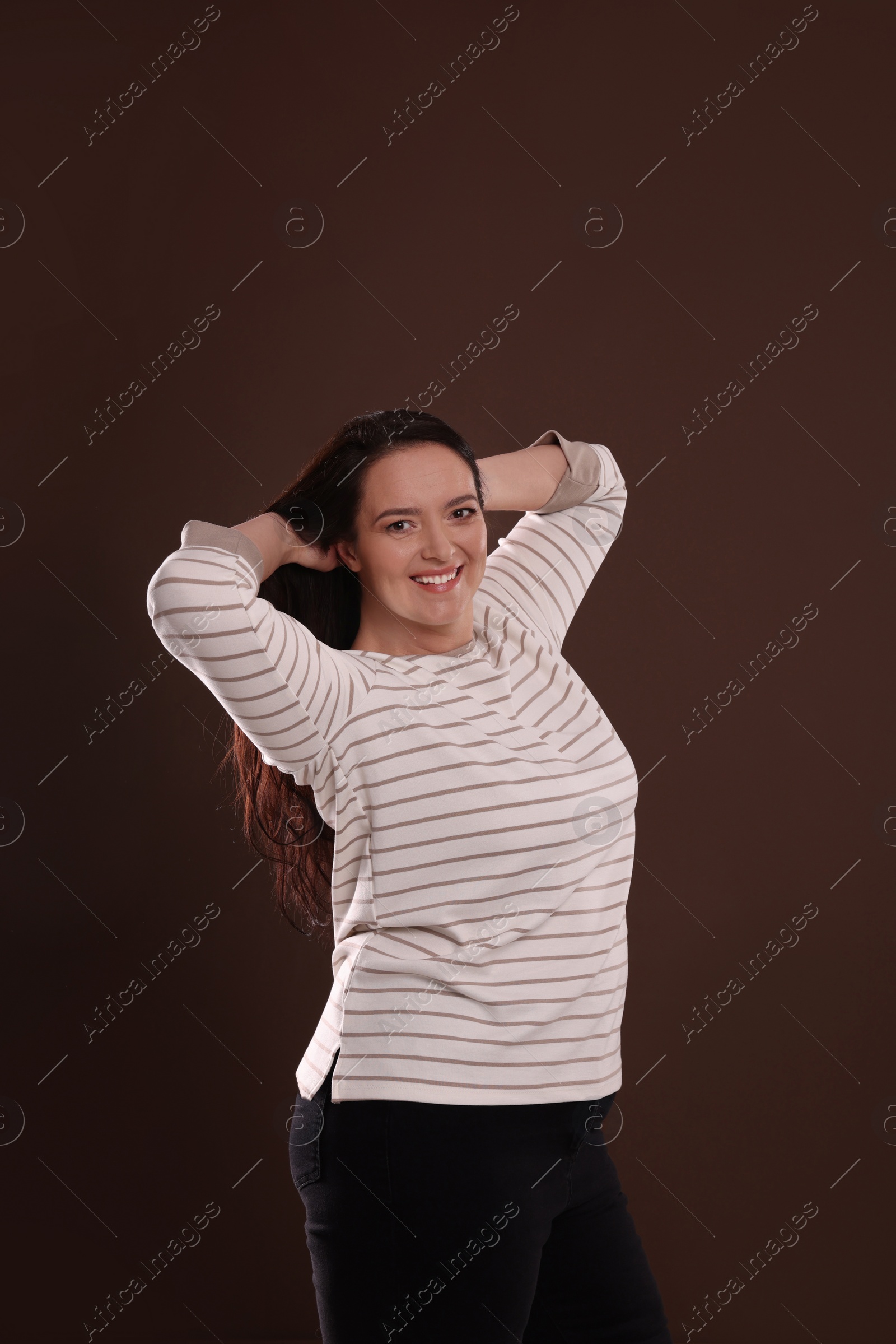 Photo of Beautiful overweight woman with charming smile on brown background