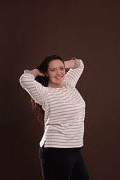 Photo of Beautiful overweight woman with charming smile on brown background