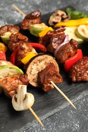 Delicious shish kebabs with vegetables on grey table, closeup