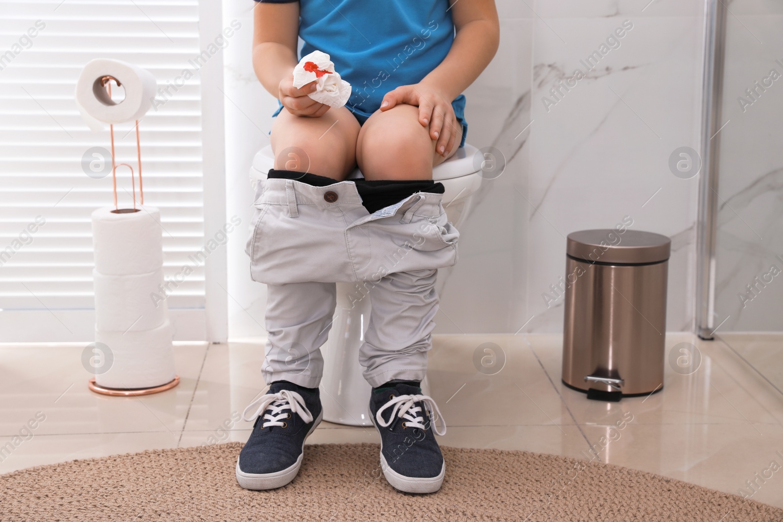 Photo of Boy holding toilet paper with blood stain in rest room, closeup. Hemorrhoid concept