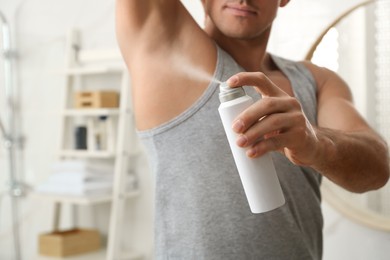 Photo of Man applying deodorant to armpit in bathroom, closeup