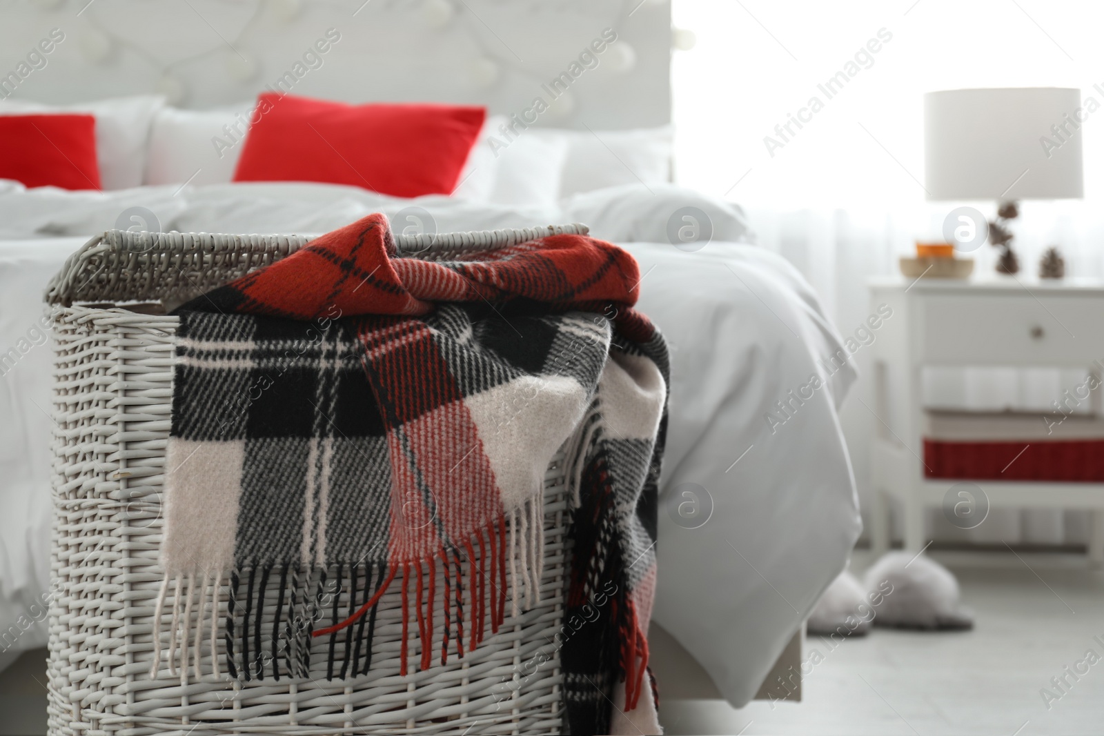 Photo of Wicker basket with warm checkered plaid in bedroom