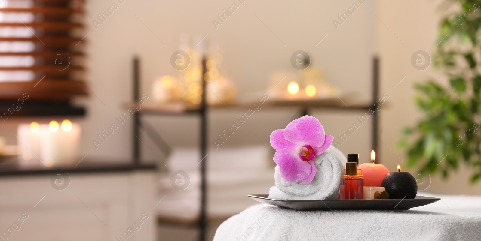 Photo of Composition with towel, candles and oils on massage table in spa salon. Space for text