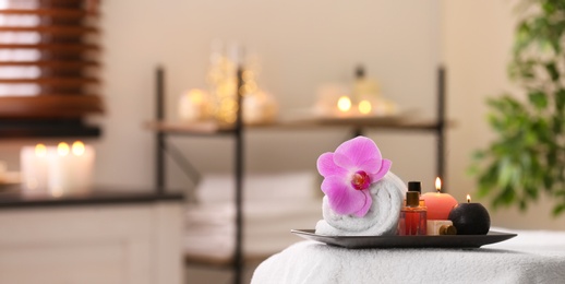 Photo of Composition with towel, candles and oils on massage table in spa salon. Space for text