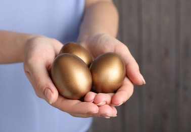Photo of Woman holding golden eggs on blurred background, closeup