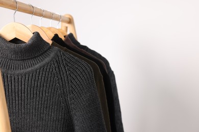 Photo of Rack with different casual sweaters on light background. Space for text