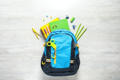 Flat lay composition with backpack and school stationery on light background