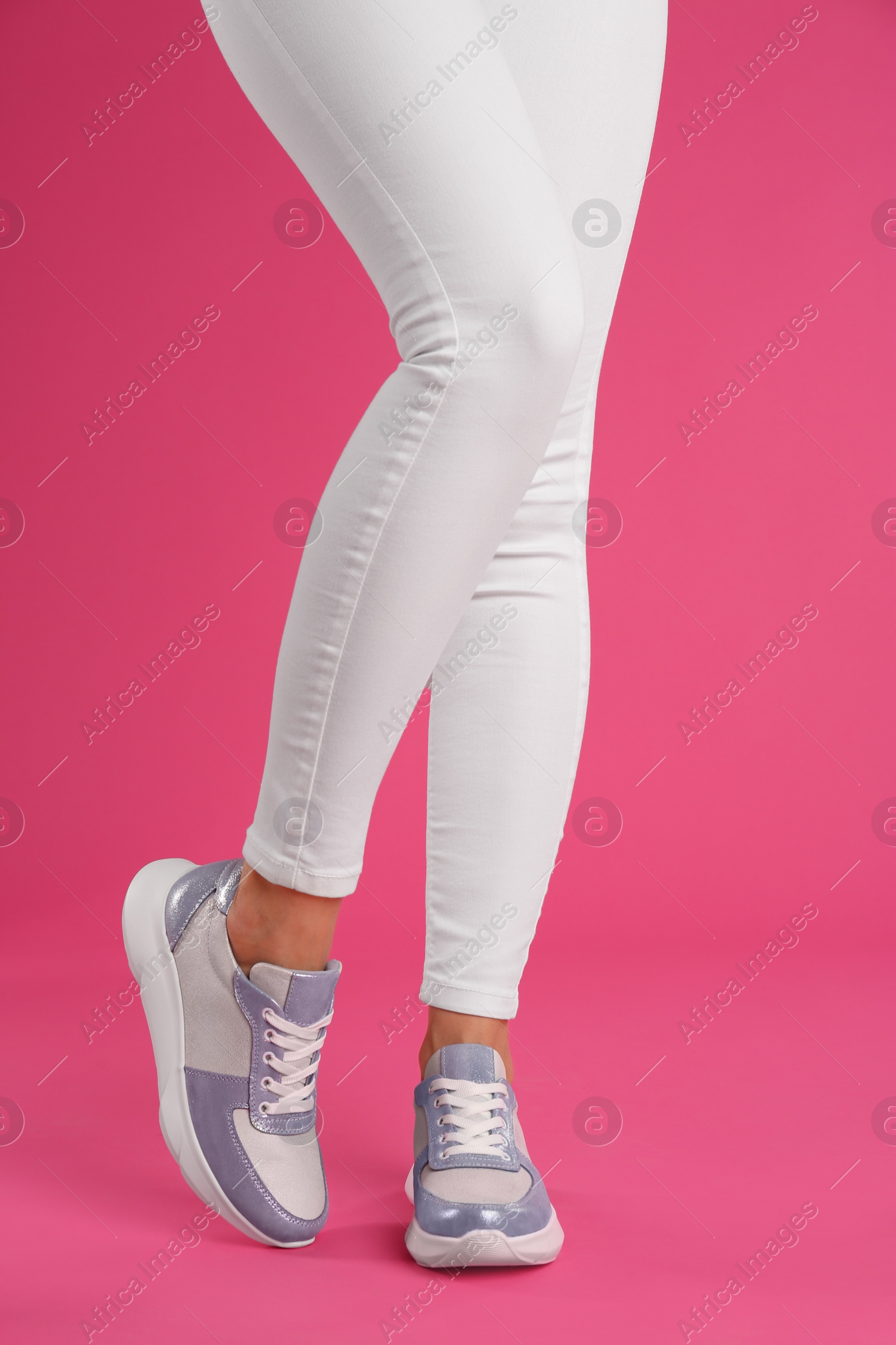 Photo of Woman wearing sneakers on pink background, closeup