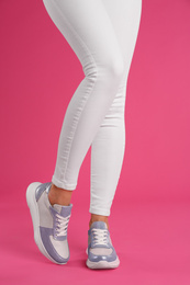 Woman wearing sneakers on pink background, closeup