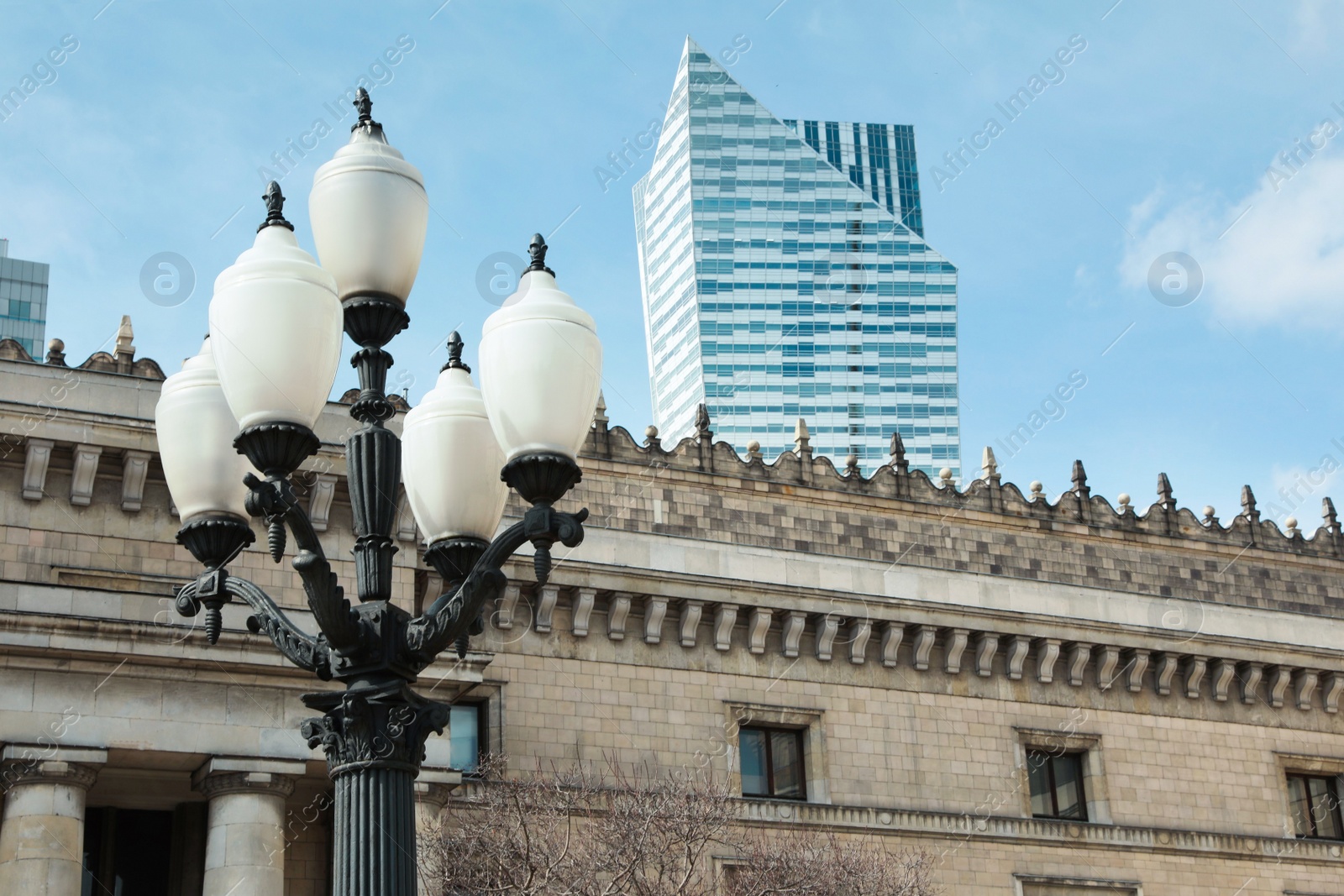 Photo of Old fashioned street light lamp near building against cloudy sky