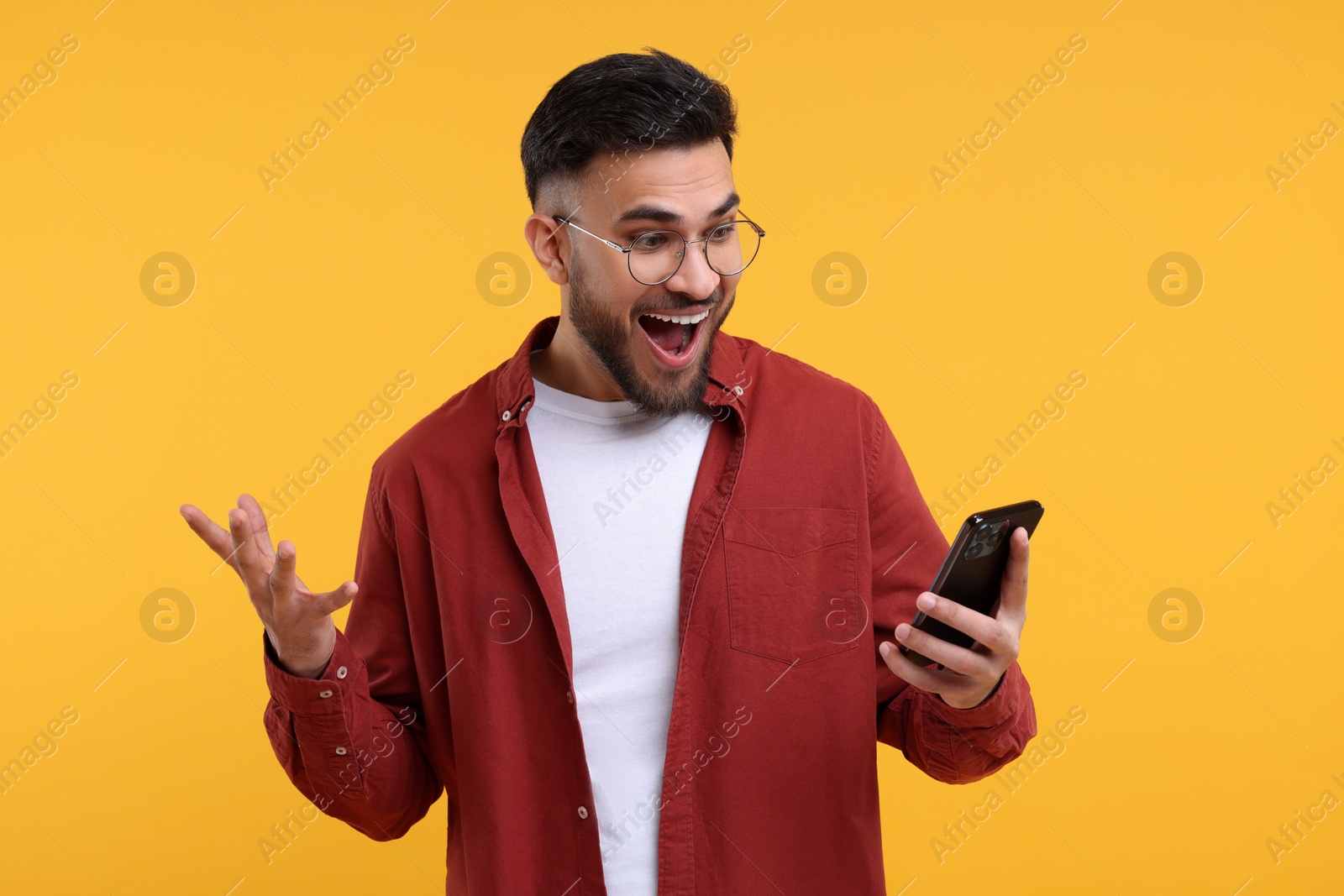 Photo of Happy young man using smartphone on yellow background