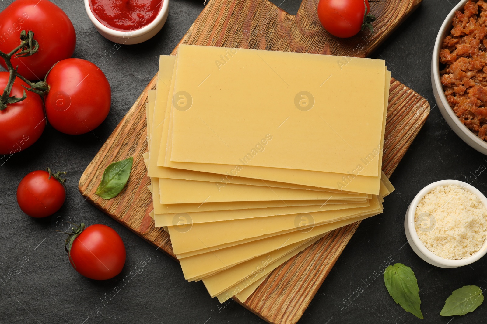 Photo of Flat lay composition with products for cooking lasagna on dark textured table