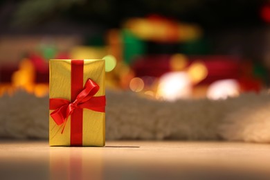 Photo of Beautiful Christmas gift with red bow on floor in room, space for text