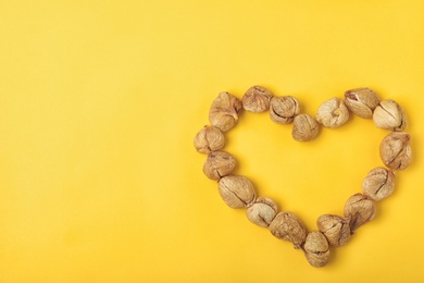 Photo of Heart shaped frame made of dried figs on color background, top view with space for text. Healthy fruit