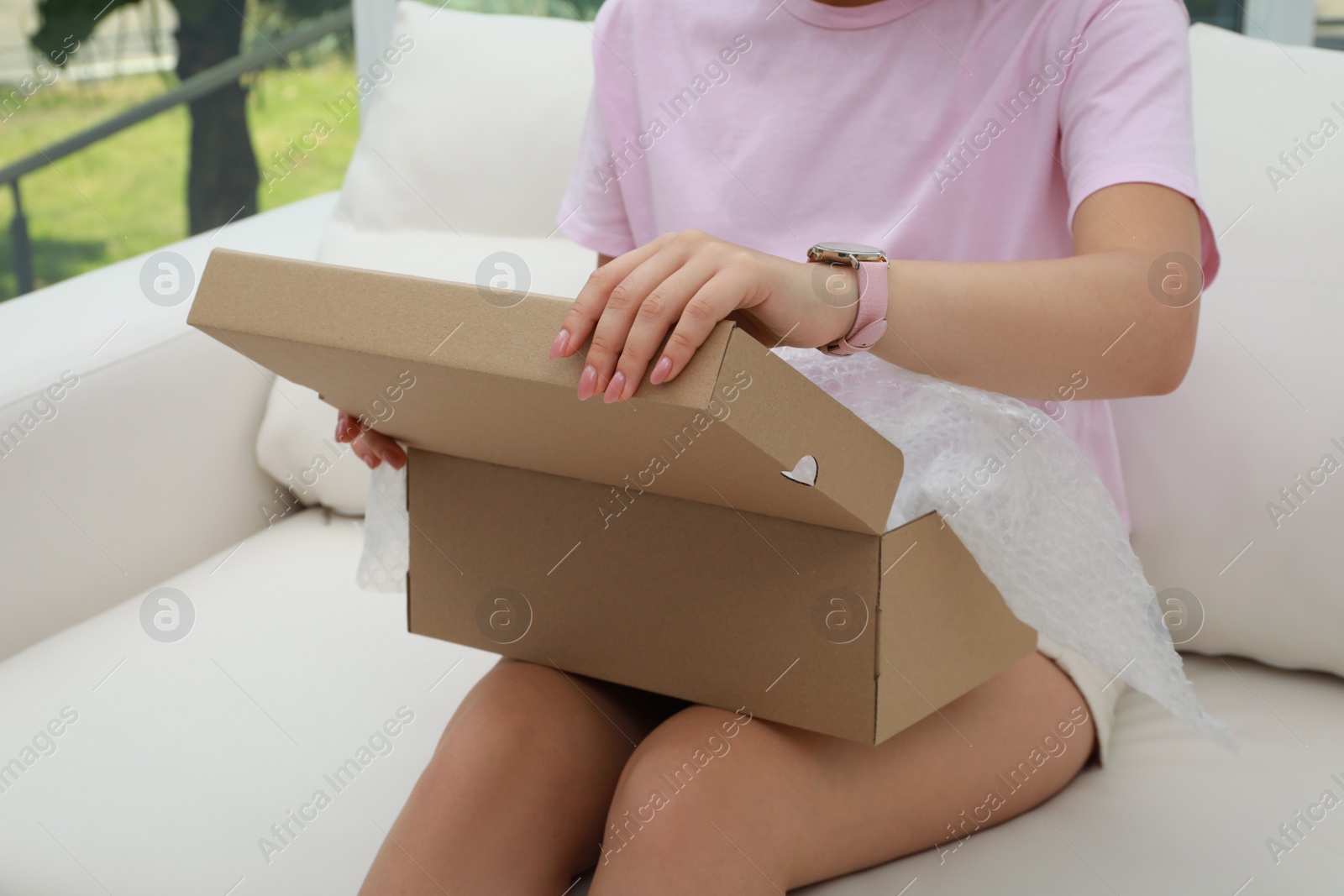 Photo of Young woman opening parcel at home, closeup. Internet shopping
