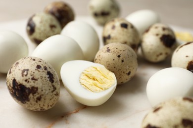 Photo of Unpeeled and peeled hard boiled quail eggs on light table, closeup