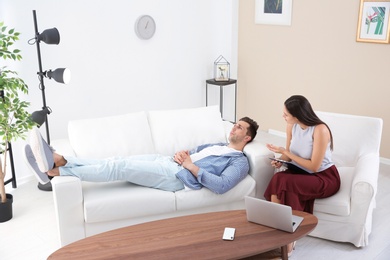 Depressed young man having appointment with psychologist in office