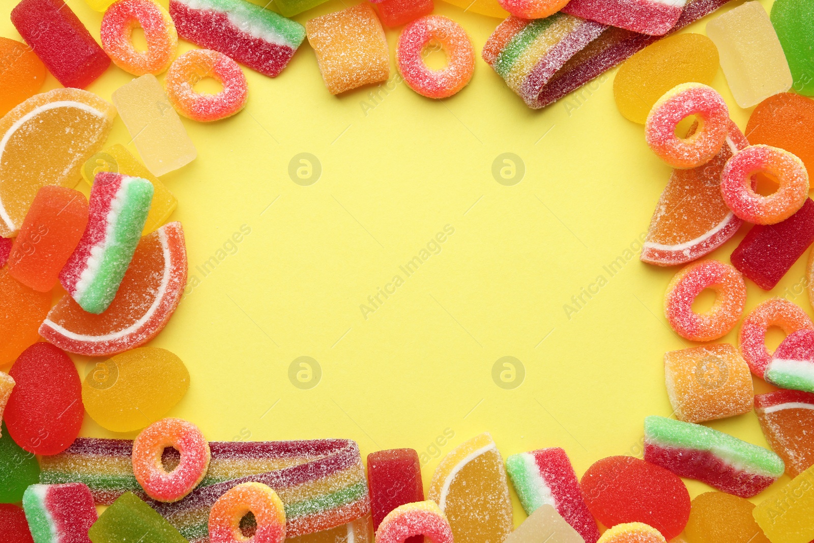 Photo of Frame made with tasty jelly candies on color background, top view. Space for text