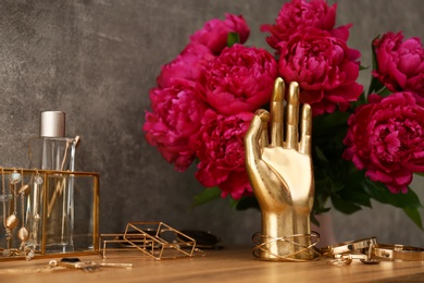 Photo of Composition with gold accessories and flowers on dressing table near grey wall