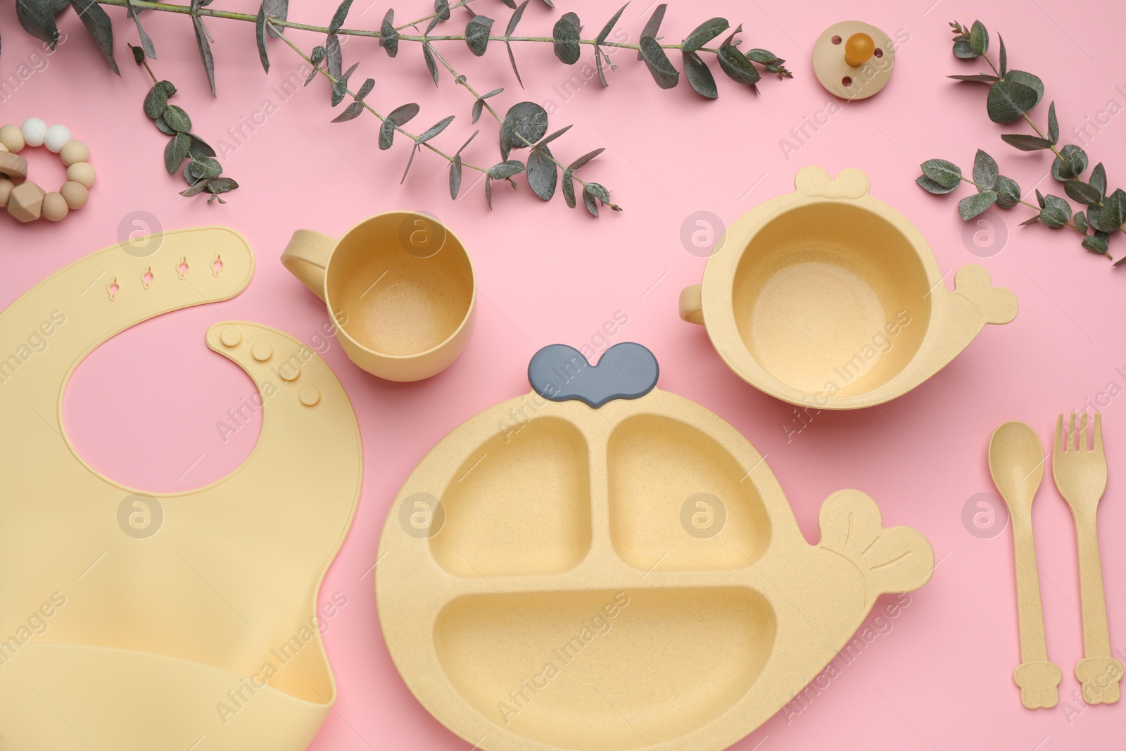 Photo of Set of plastic dishware and baby accessories on pink background, flat lay