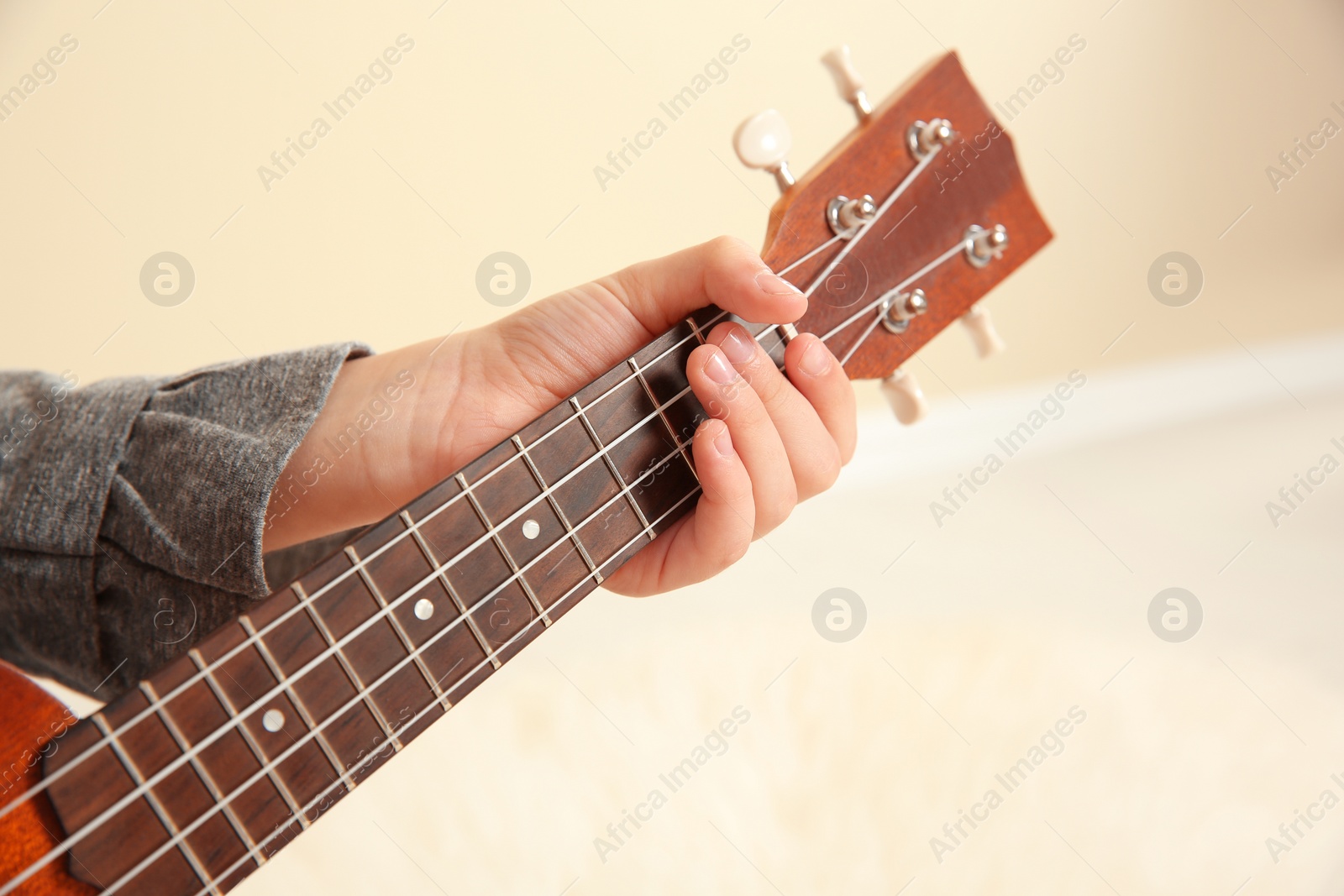 Photo of Little girl playing wooden guitar indoors, closeup