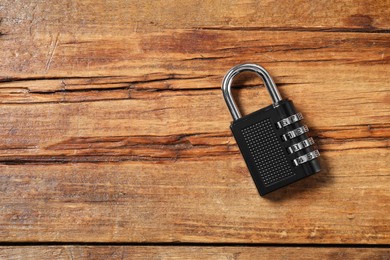 Photo of One steel combination padlock on wooden table, top view. Space for text