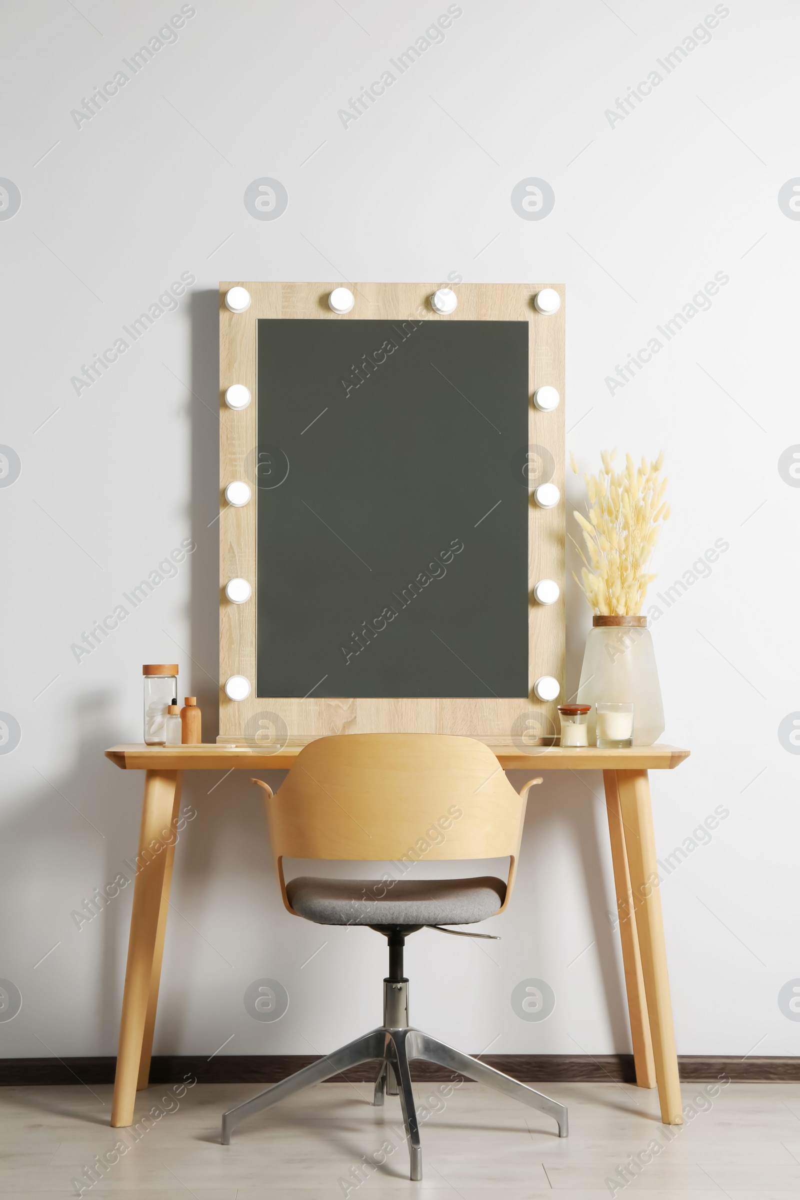 Photo of Dressing table with stylish mirror, dried reeds and other decorative elements. Interior design