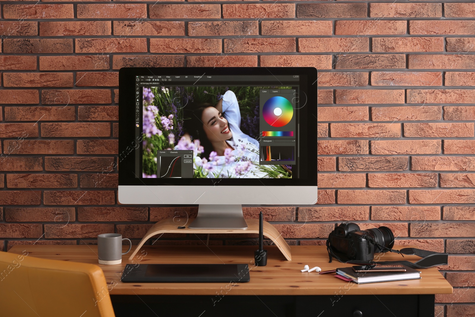 Photo of Modern retoucher's workplace with different digital devices on wooden table near red brick wall