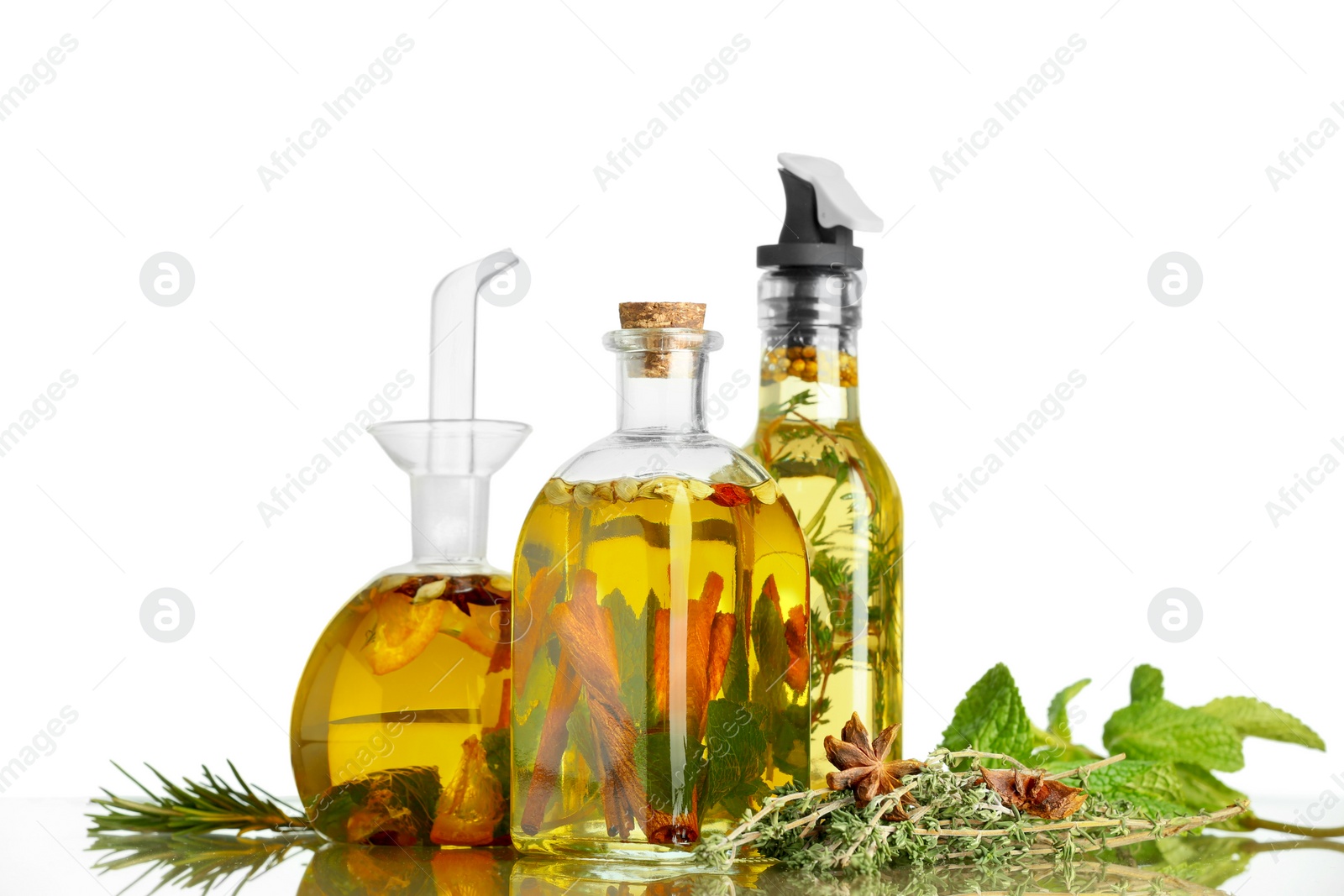 Photo of Cooking oil with different spices and herbs in bottles on light table