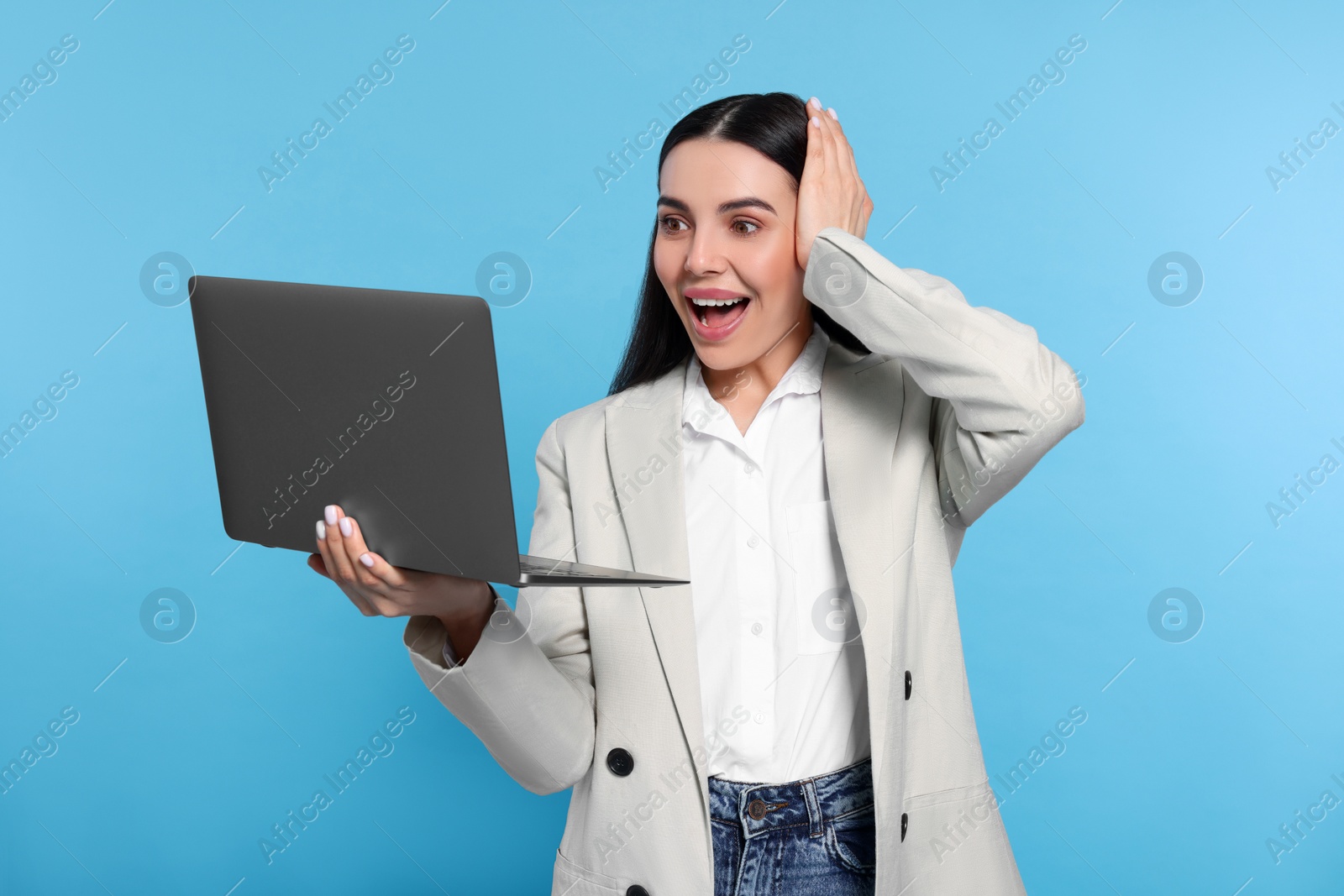 Photo of Emotional woman with laptop on light blue background