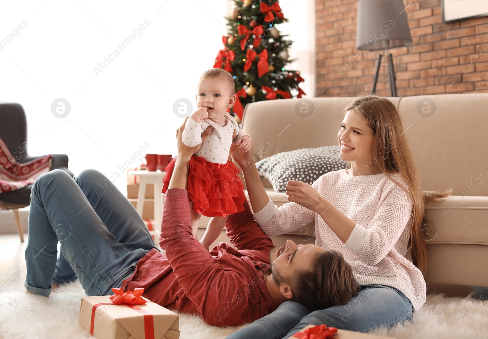 Photo of Happy couple with baby celebrating Christmas together at home