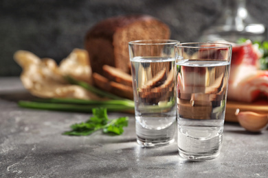 Photo of Cold Russian vodka with snacks on grey table, closeup