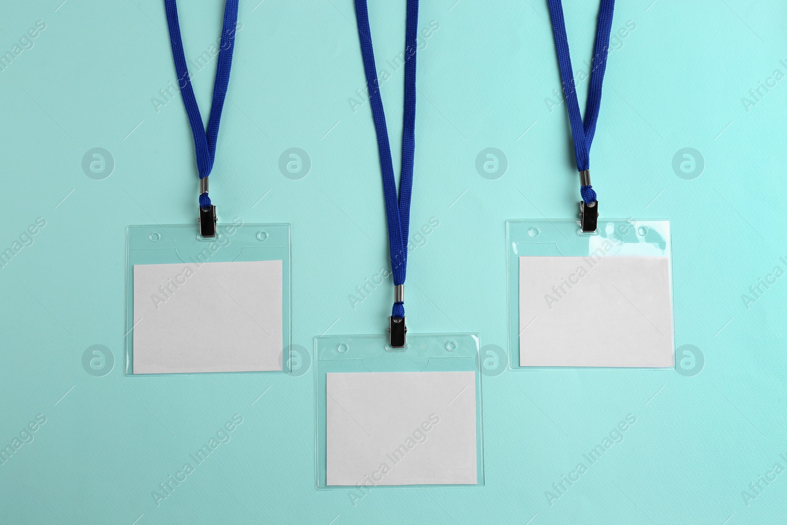 Photo of Blank badges on turquoise background, flat lay. Mockup for design