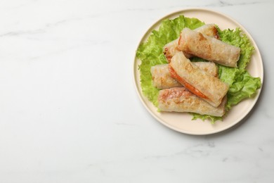 Photo of Delicious fried spring rolls on white table, top view. Space for text