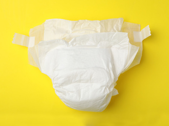 Photo of Baby diaper on yellow background, top view