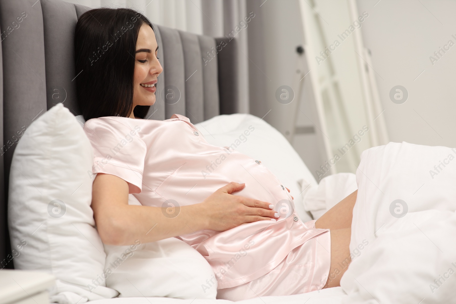 Photo of Happy pregnant woman in bed at home