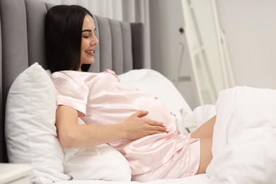 Photo of Happy pregnant woman in bed at home
