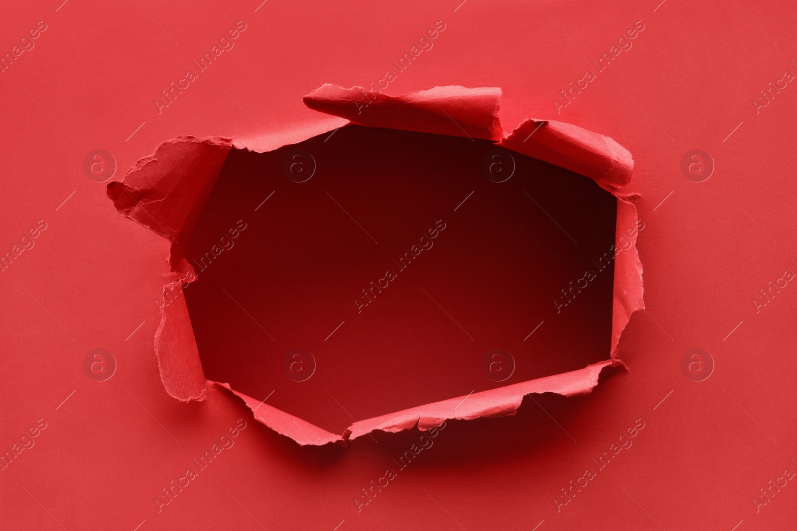 Photo of Hole in red paper on color background